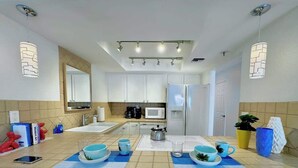 A modern kitchen with white cabinets, a central island, and pendant lighting. - Downtown Palm Springs Holiday Loft, View Patio (Palm Springs)