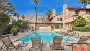 A pool area with lounge chairs, a pool, and a building with a mountain backdrop. - Downtown Palm Springs Holiday Loft, View Patio (Palm Springs)