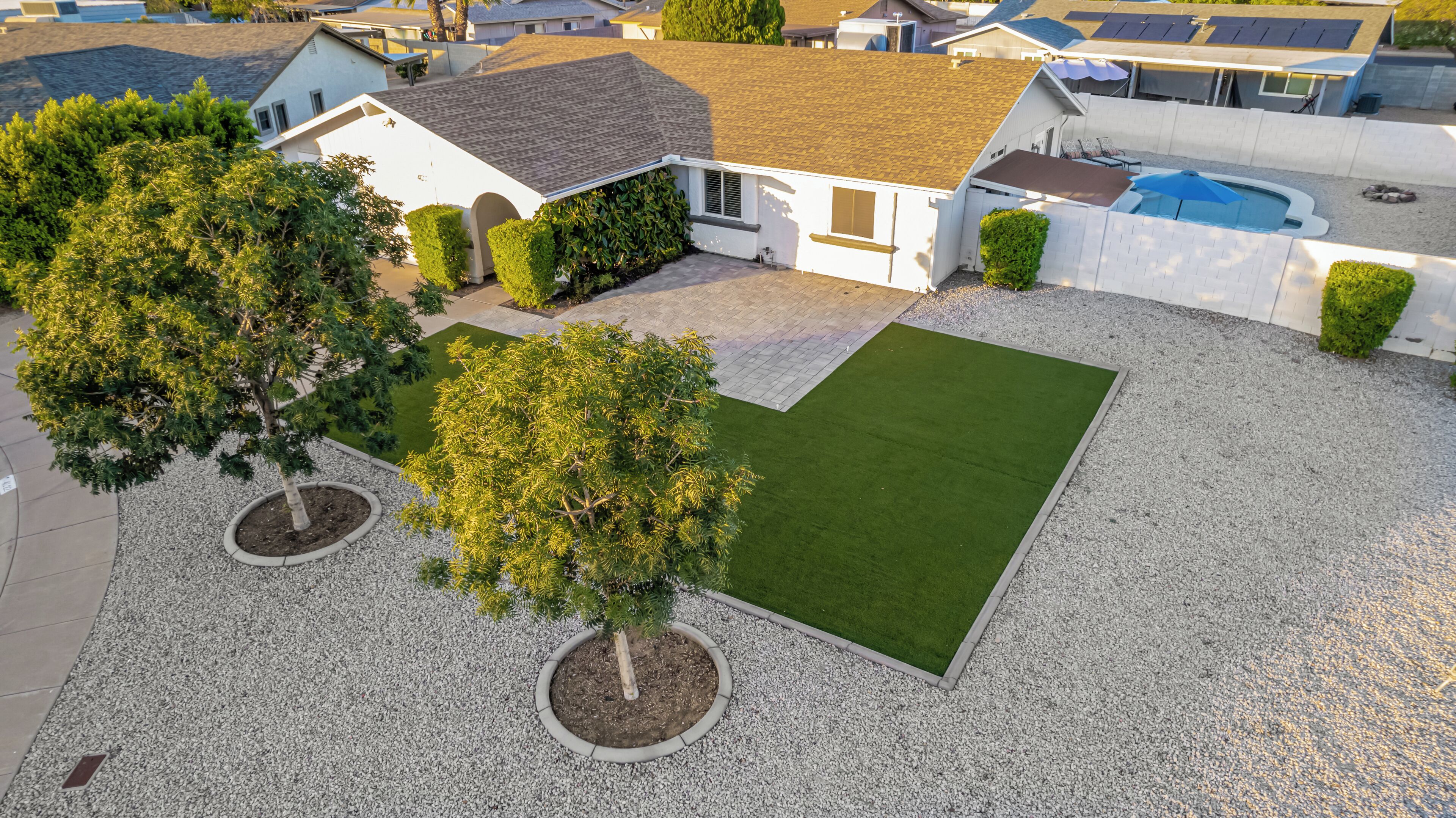 A residential property with a paved driveway, a lawn, and a swimming pool.