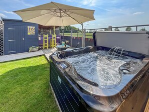 A hot tub with a control panel, a wooden deck, and a covered seating area with a table and chairs. - 2 bedroom accommodation in Crowle (Crowle)