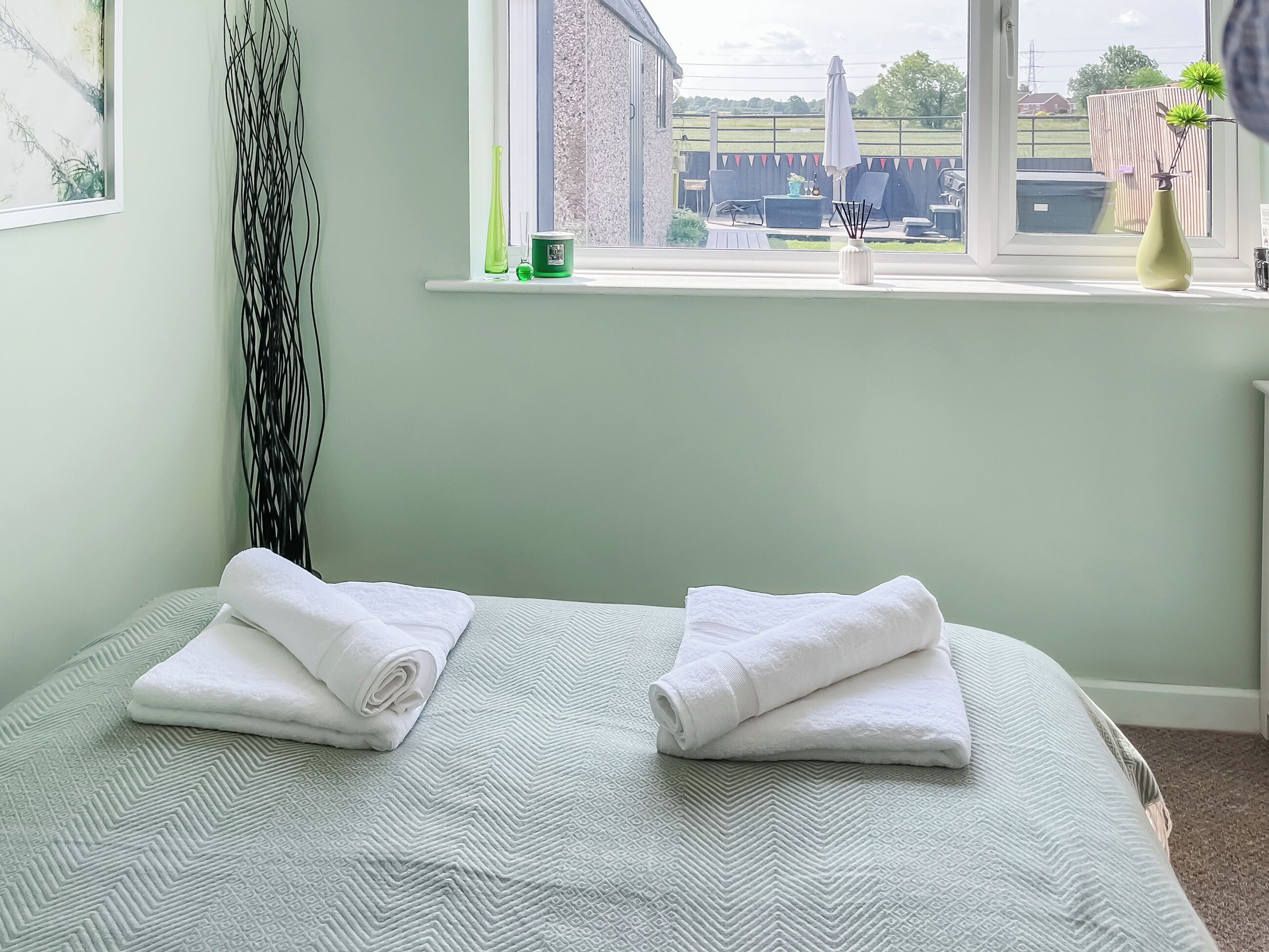 A room with a bed, a window with a view of the outside, and a curtain.