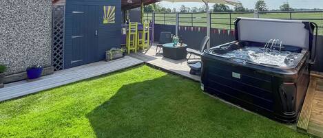 Un jardin avec un jacuzzi, du mobilier d’extérieur et une pergola.