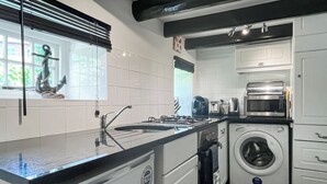 A compact kitchen with a sink, stove, microwave, and washing machine.