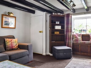 Ein gemütliches Wohnzimmer mit Sofa, Hocker und Bücherregal.