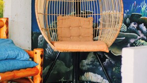 A wicker chair with a cushion, a wooden stool, and a wall mural of an underwater scene.