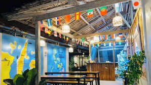 An indoor dining area with wooden tables and benches, a map on the wall, and flags hanging from the ceiling.