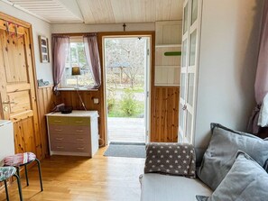 A cozy room with a wooden floor, a sofa, a small table with a lamp, and a window with curtains. - 4 Person Holiday Home in Borgholm (Borgholm)
