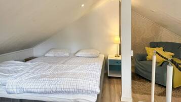 A bedroom with a bed, a nightstand, a lamp, and a sofa.