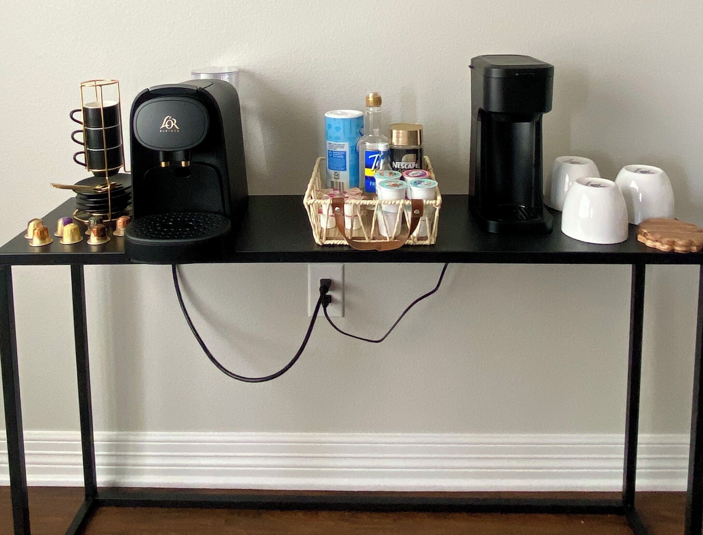 Una estación de café con una cafetera, un cesto de cápsulas de café, una máquina Nespresso y un molinillo.