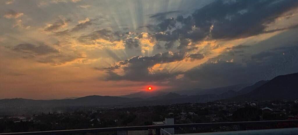 Um pôr do sol sobre uma paisagem urbana com montanhas ao fundo.
