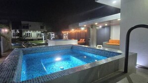 A swimming pool with a tiled edge, a covered seating area with orange cushions, and a modern building in the background. - Serenity Loft for relaxation with pool in Oaxtepec (Oaxtepec)