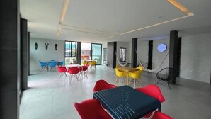 A modern dining area with red and yellow chairs, a central table, and a view of the outdoors through large windows. - Serenity Loft for relaxation with pool in Oaxtepec (Oaxtepec)