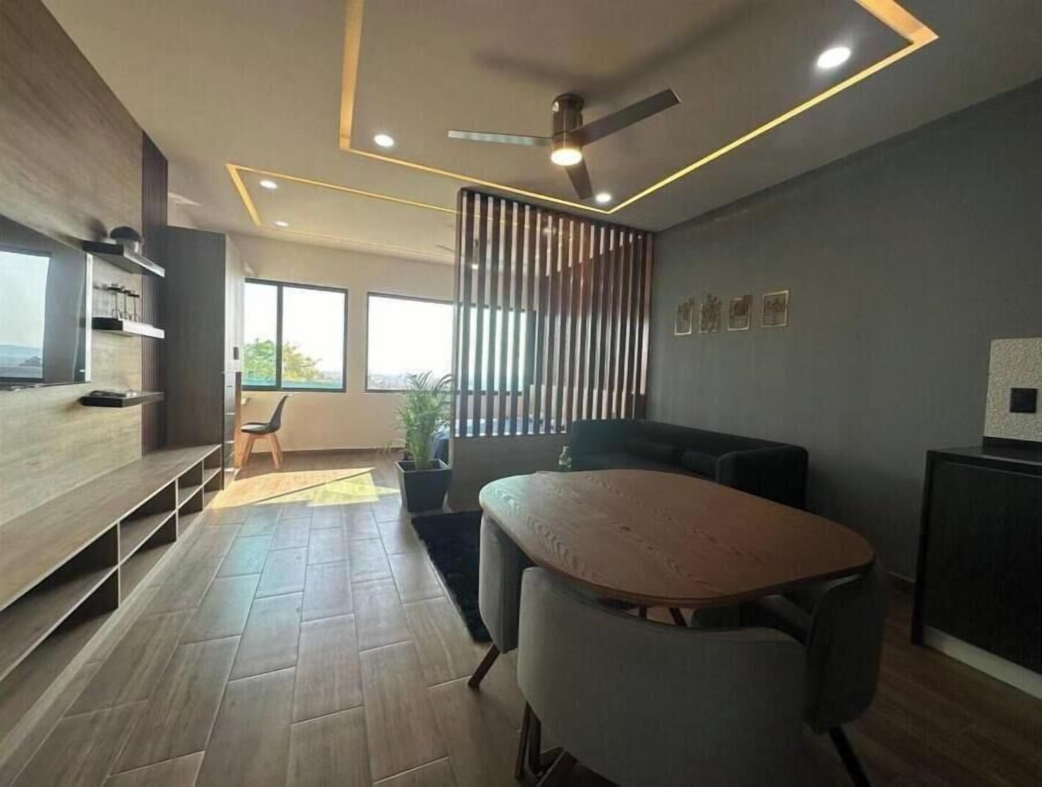 A modern interior with a dining area, a sofa, a ceiling fan, and a view through large windows.