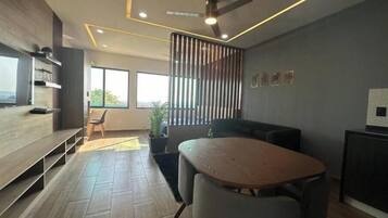 A modern interior with a dining area, a sofa, a ceiling fan, and a view through large windows.