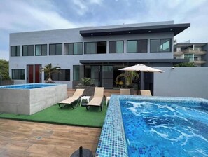 Uma casa moderna com piscina, duas espreguiçadeiras e um espaço de varanda.