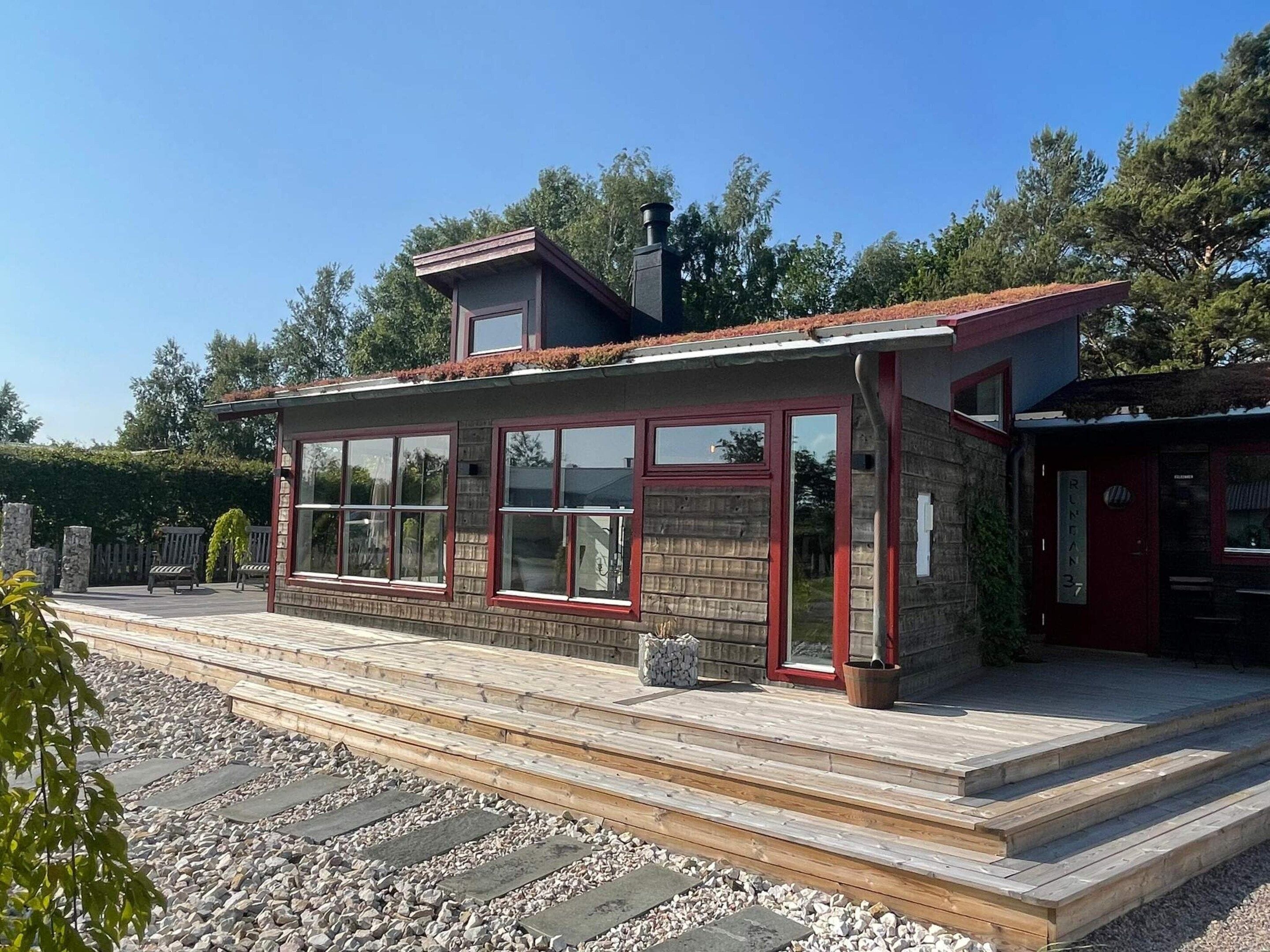 A two-story building with a wooden deck, large windows, and a chimney.