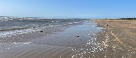 A beach with a wide sandy shore and gentle waves.