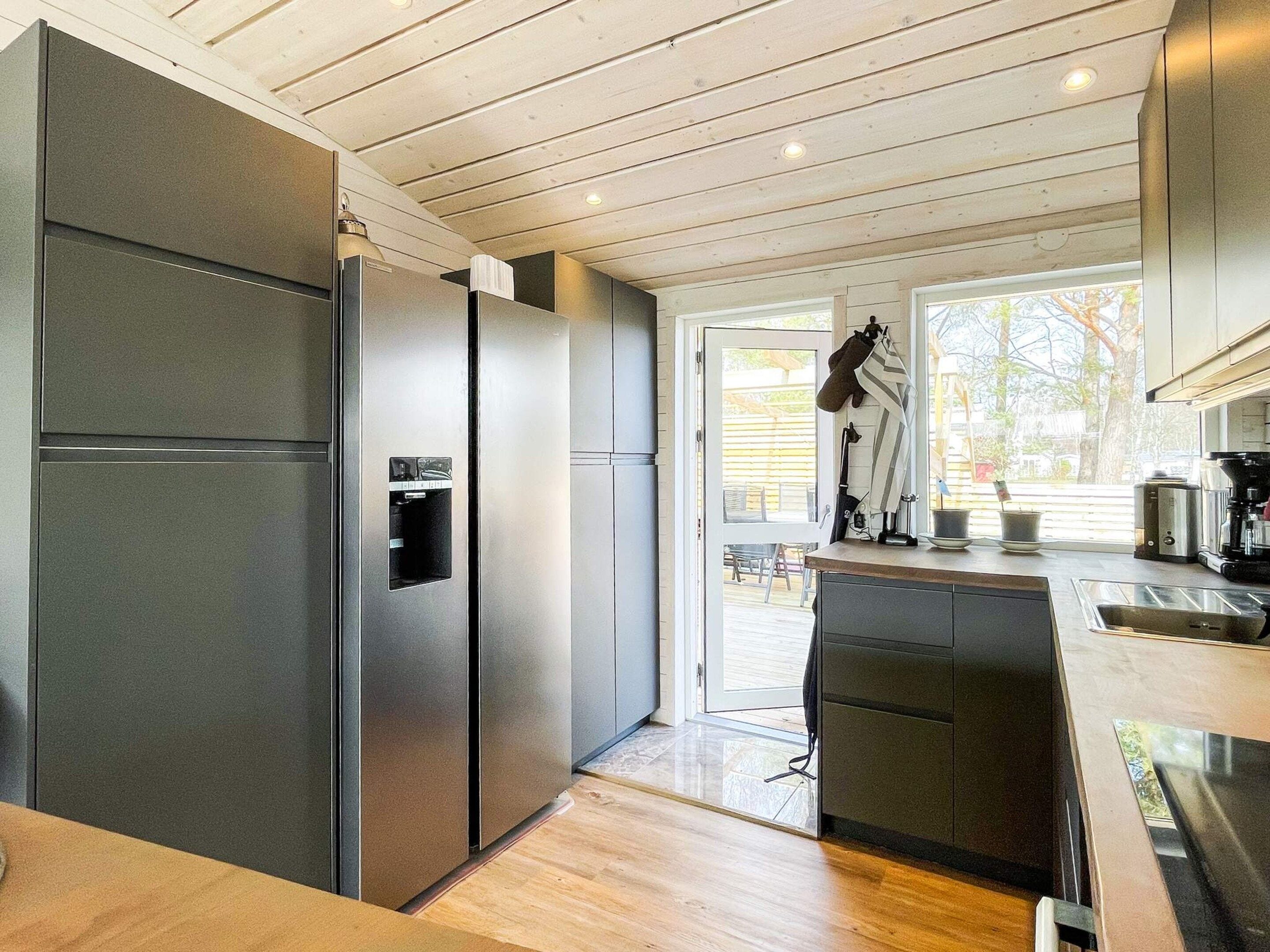 Une cuisine moderne dotée d’appareils électroménagers en acier inoxydable, d’un plafond en bois et offrant une vue sur l’extérieur.
