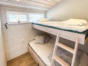 Une chambre avec un lit superposé, une fenêtre, des murs en bois et une échelle.
