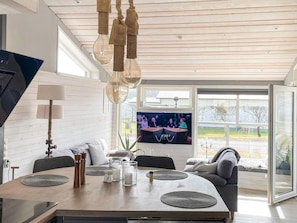 Een moderne woonkamer met een eethoek, een televisie en uitzicht op het buiten.