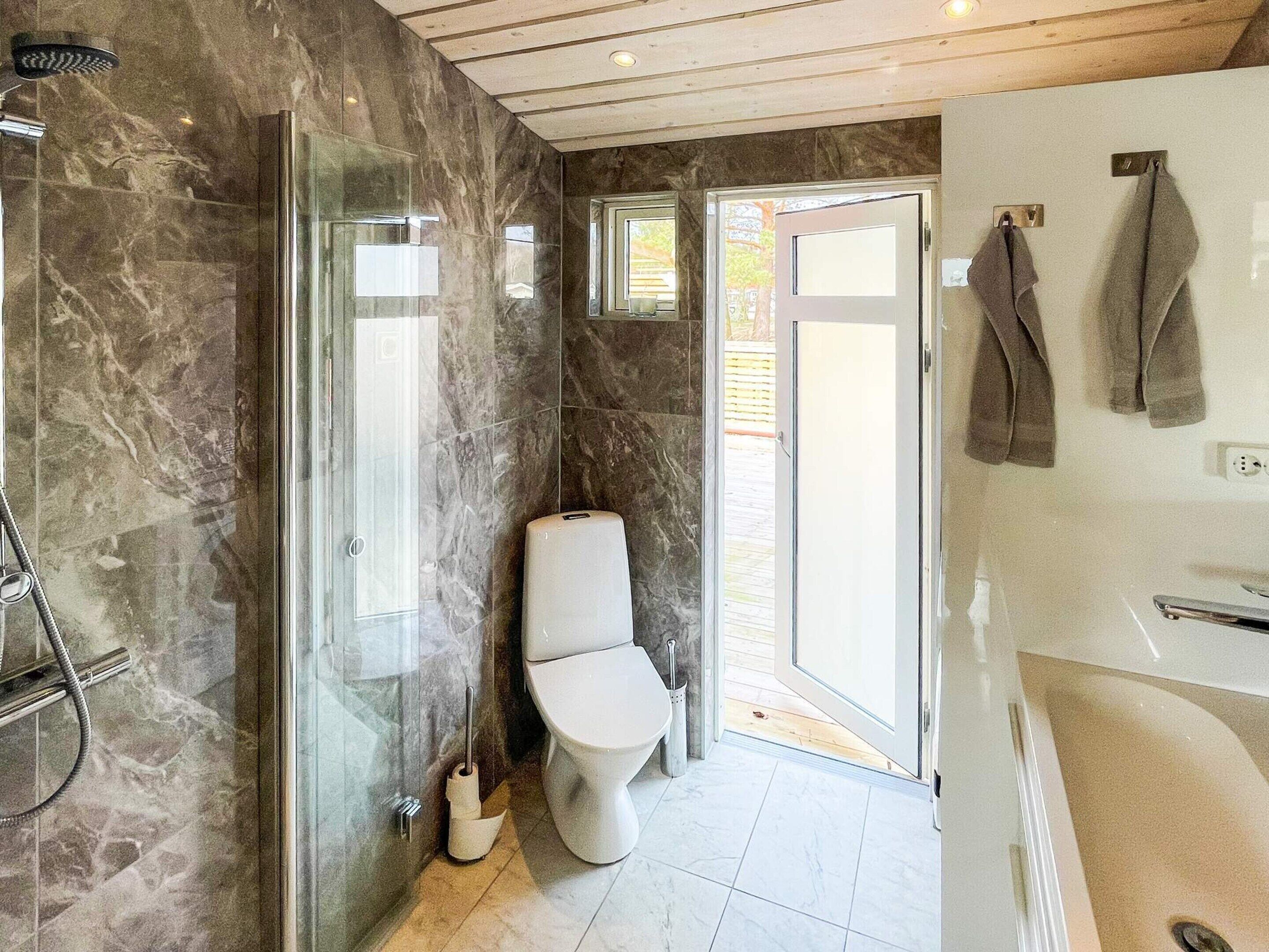A modern bathroom with a glass-enclosed shower, a toilet, and a bathtub.