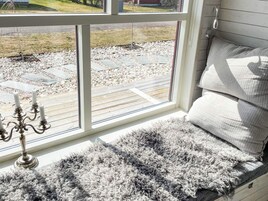 A room with a large window, a cushioned bench, and a candelabra.