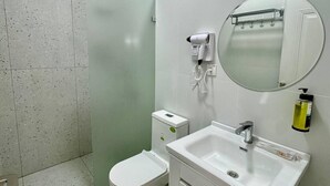 A modern bathroom with a toilet, sink, and a handheld hair dryer mounted on the wall. - Bogdon Grand Hotel (Tashkent)