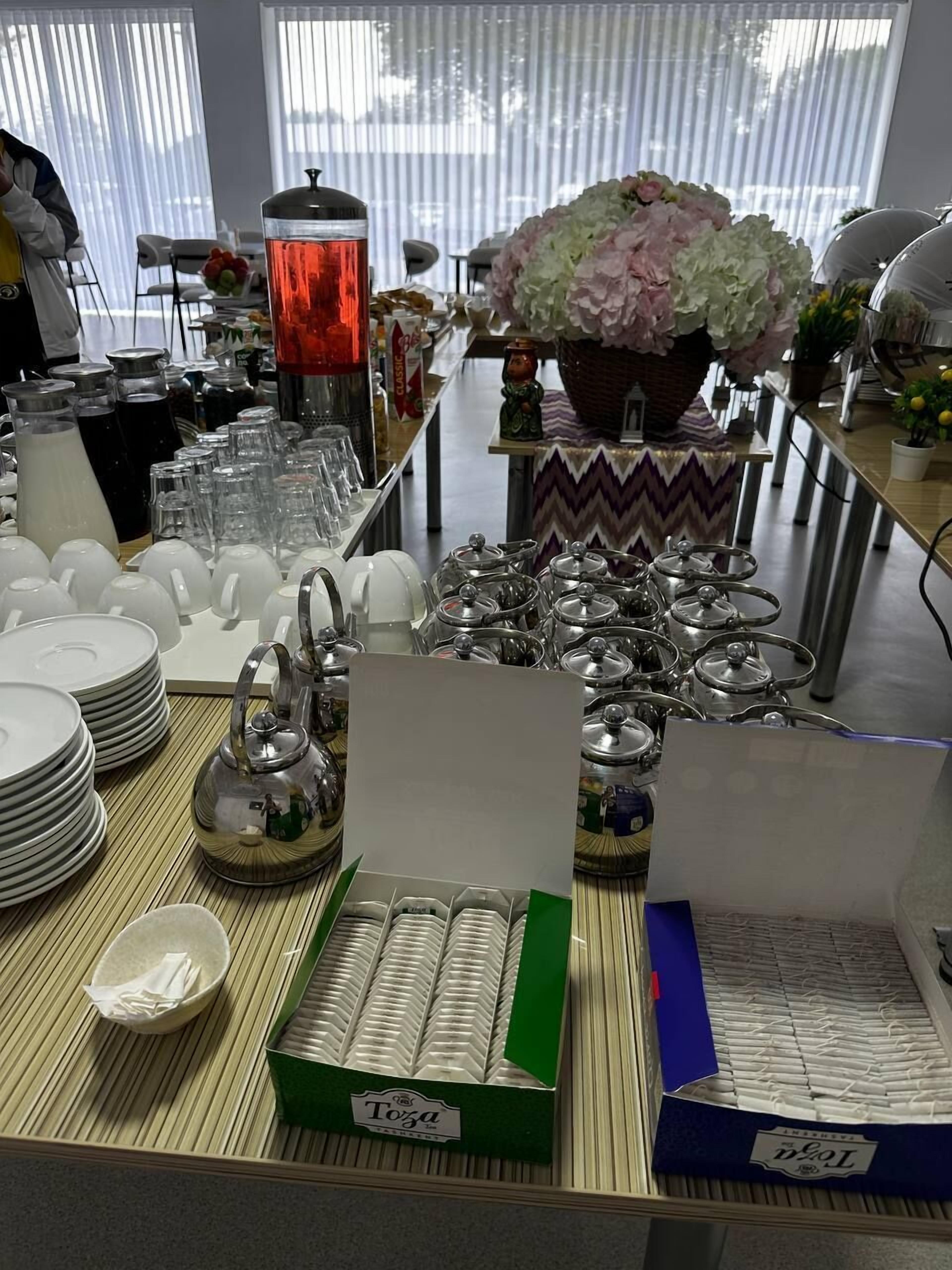 A buffet setup with various dishes, glassware, and a decorative floral arrangement.