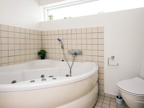 A bathroom with a freestanding bathtub, a toilet, and a small potted plant. - 5 Star Holiday Home in Hemmet (Hemmet)