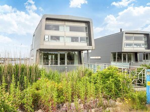 A modern two-story building with large windows, a flat roof, and a visible outdoor area with vegetation. - 5 Star Holiday Home in Hemmet (Hemmet)