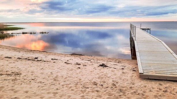 A wooden pier extending into calm waters with a sandy beach on one side. - 5 Star Holiday Home in Hemmet (Hemmet)
