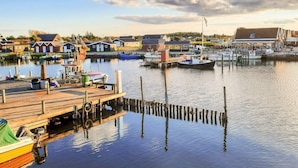 A marina with boats docked, a wooden pier, and buildings in the background. - 5 Star Holiday Home in Hemmet (Hemmet)