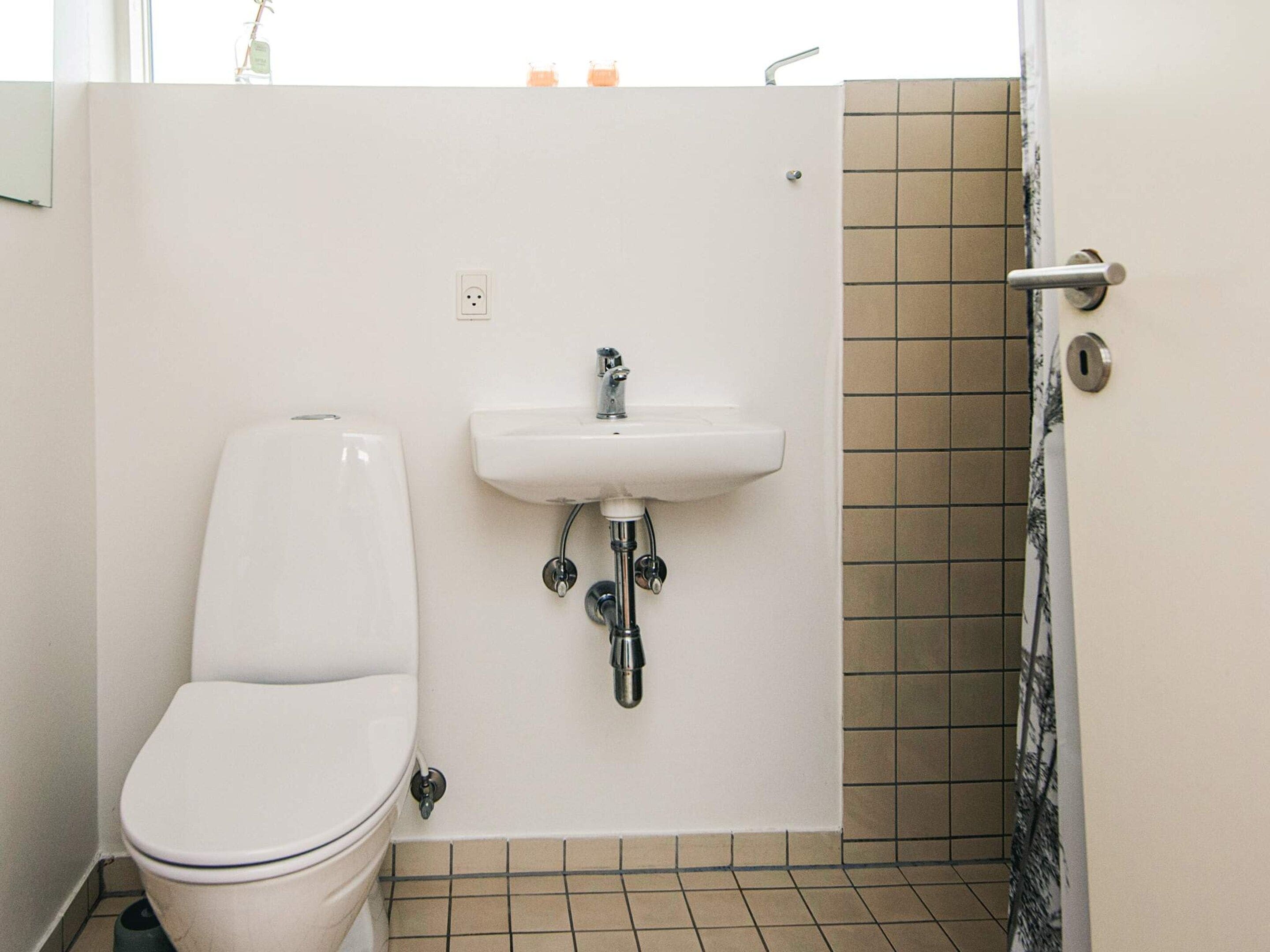 Ein Badezimmer mit Toilette, Waschbecken und Duschbereich.