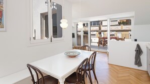 A dining area with a white table, wooden chairs, and a decorative bowl. There is a large window with a view of the outside. - Solaga - Alba (Málaga)