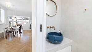 A modern kitchen with a dining area, a large window, and a white countertop with a blue bowl sink. - Solaga - Alba (Málaga)