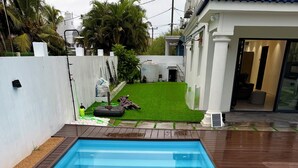 Ein rechteckiger Swimmingpool mit einer ihn umgebenden Holzterrasse.