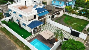 Ein mehrstöckiges Wohngebäude mit Pool auf dem Dach, einer überdachten Terrasse und einem grünen Rasen.