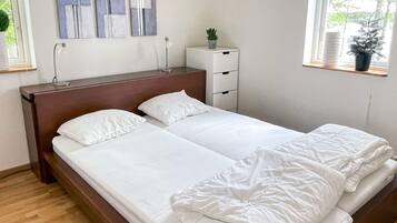 A double bed with white bedding, a nightstand with a lamp, and abstract wall art.
