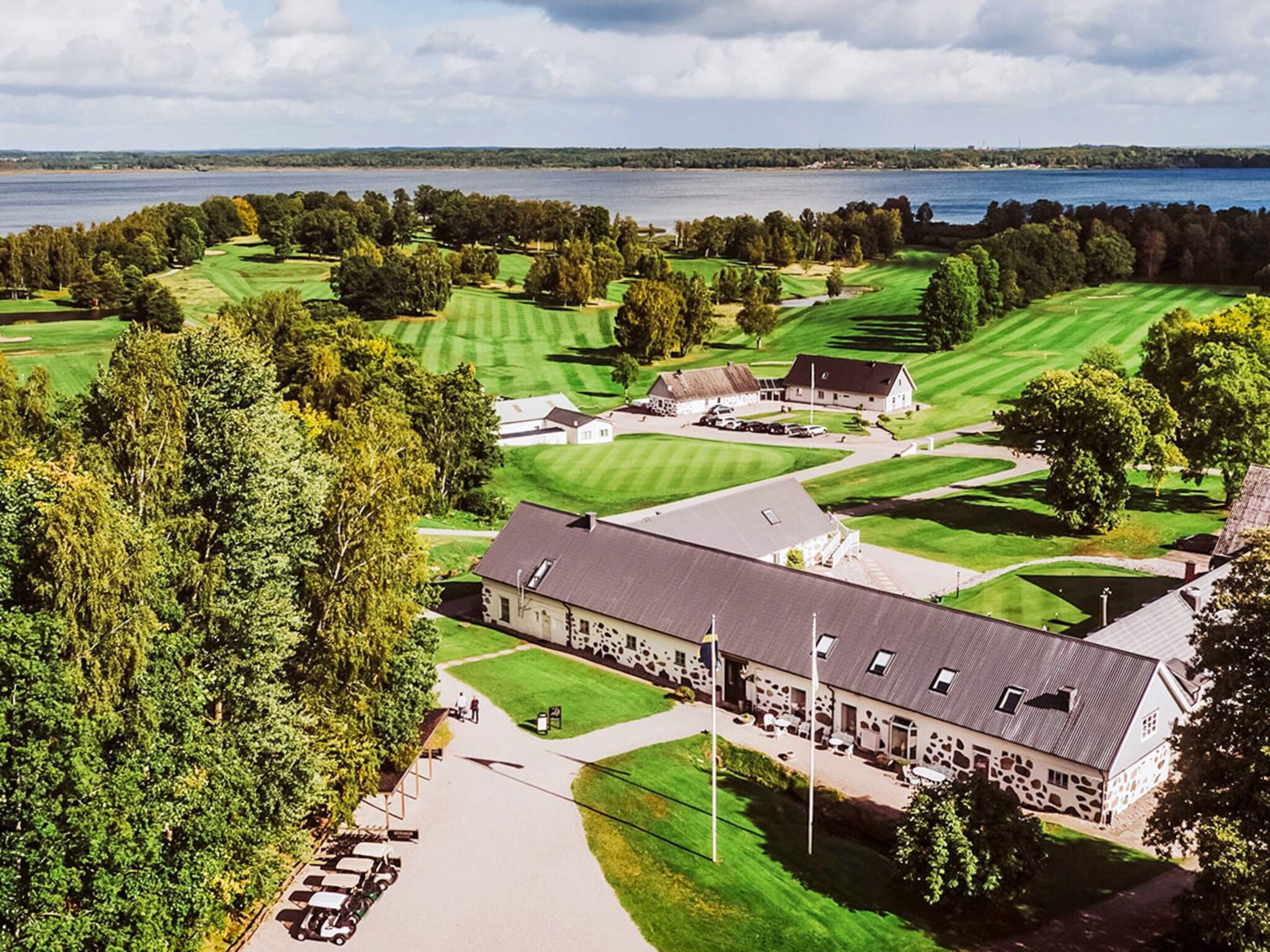 A golf course with a clubhouse and a large building with a stone facade.