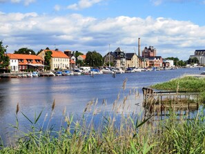 Une ville riveraine dotée de bâtiments historiques, d’un port de plaisance avec des bateaux et d’un plan d’eau paisible.