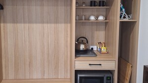 A kitchen with wooden cabinets, a kettle, a microwave, and a coffee maker.