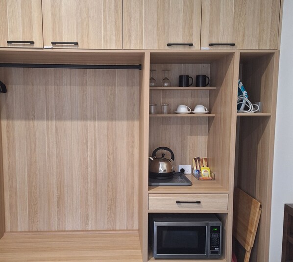 Eine Küche mit Holzschränken, einem Wasserkocher, einer Mikrowelle und einer Kaffeemaschine.