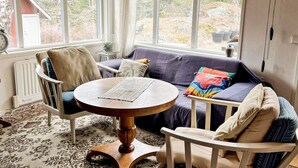 A cozy room with a round wooden table, a cushioned sofa, and a chair. - 5 Person Holiday Home in Ingaro (Ingaro)