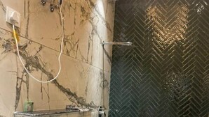 Un baño con tocador de mármol, inodoro y zona de ducha con revestimiento en patrón de espiga.