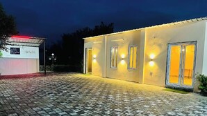 Un edificio moderno con un área de entrada pavimentada y ventanas iluminadas.