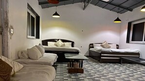Una habitación con dos camas, un sofá y una mesa de centro de vidrio.