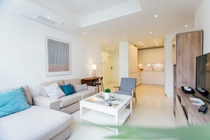 Ein modernes Wohnzimmer mit einer Couch, einem Sessel, einem Couchtisch und einem TV-Schrank.