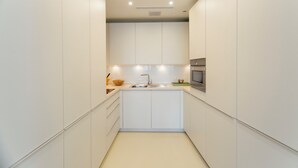 A modern kitchen with white cabinetry, a central island, and built-in appliances. - Preciosas Vistas a Catedral (Seville)
