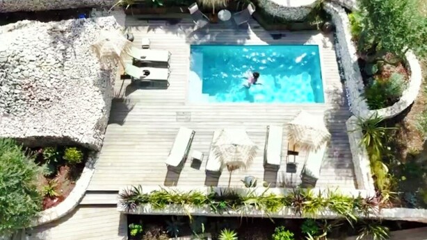 An aerial view of a pool area with a rectangular pool, lounge chairs, and surrounding vegetation. - Maison Mahana (Bonifacio)