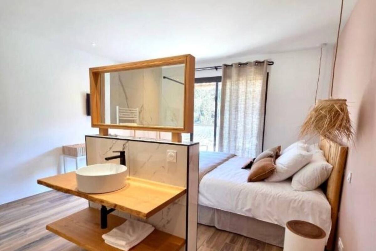 Un baño moderno con tocador de madera, un espejo grande y un lavamanos blanco.